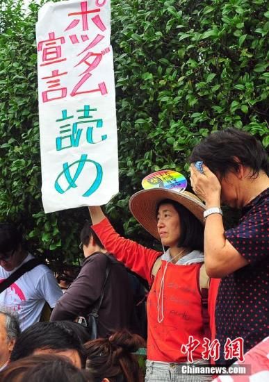 资料图：8月30日，日本人国一名示威者高举“读一读波茨坦宣言”的千多标语牌，对安倍作为表示不满。议会国会集<strong></strong> 王健 摄