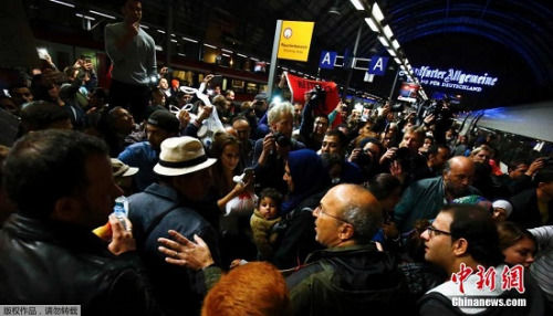 在德国法兰克福火车站，一个抵达的难民家庭被当地接待的人士团团围住。